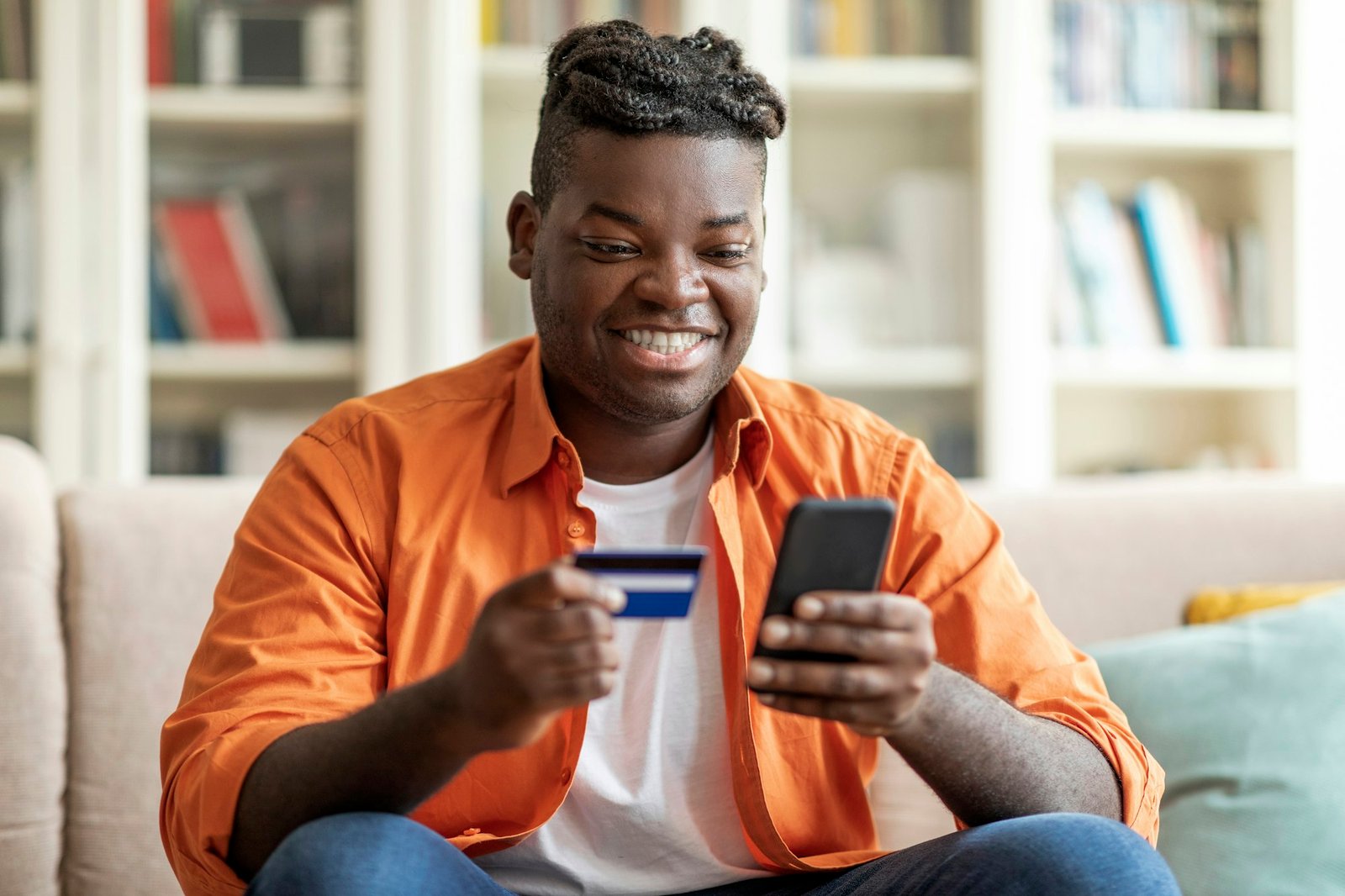 Cheerful african man using smartphone and bank card