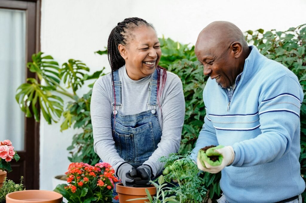 Happy farmer African senior couple gardening outdoor in home backyard terrace